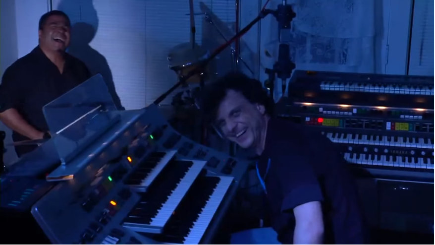 In the Moment (New Album) Behind the Scenes Picture: Composer Miguel Kertsman on the keyboards and Ernie Adams on the drums. They are looking in the camera, laughing.